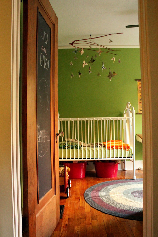 Inspiration pour une chambre de bébé garçon bohème avec un mur vert et un sol en bois brun.