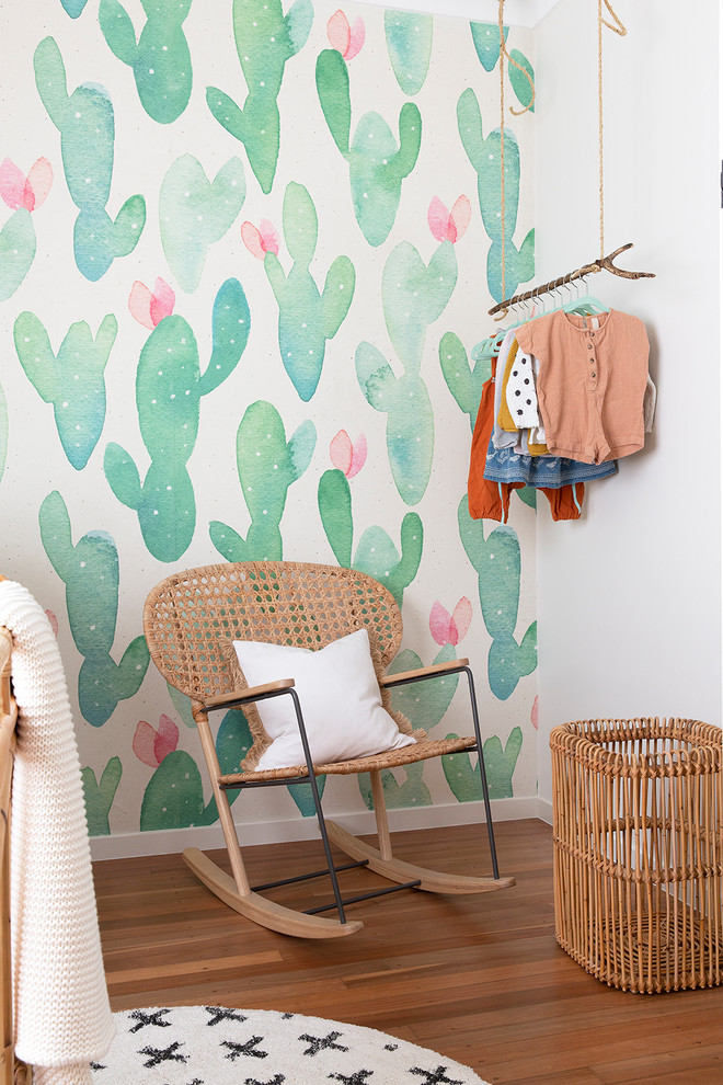 Réalisation d'une chambre de bébé fille marine avec un mur multicolore et un sol en bois brun.