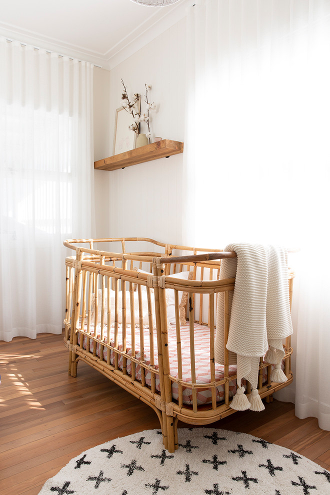 Imagen de habitación de bebé niña marinera con paredes beige y suelo de madera en tonos medios