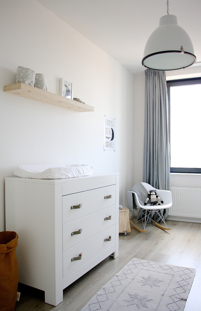 Photo of a scandi gender neutral nursery in Amsterdam with white walls, light hardwood flooring and beige floors.