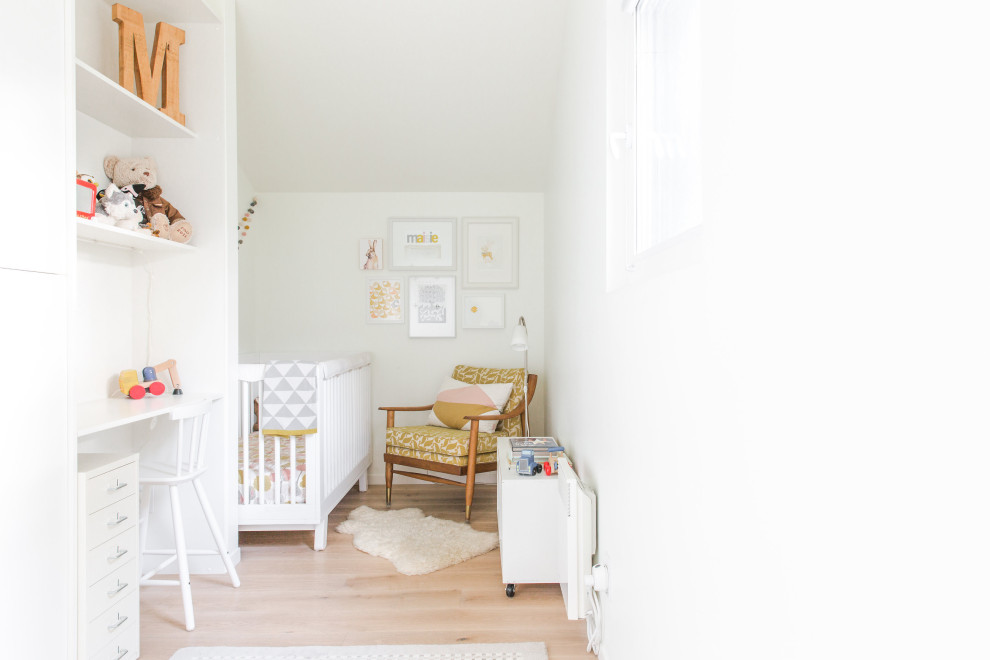 Immagine di una piccola cameretta per neonati neutra scandinava con pareti bianche, parquet chiaro e pavimento beige