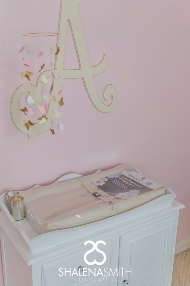 Immagine di una cameretta per neonata minimal con pareti rosa