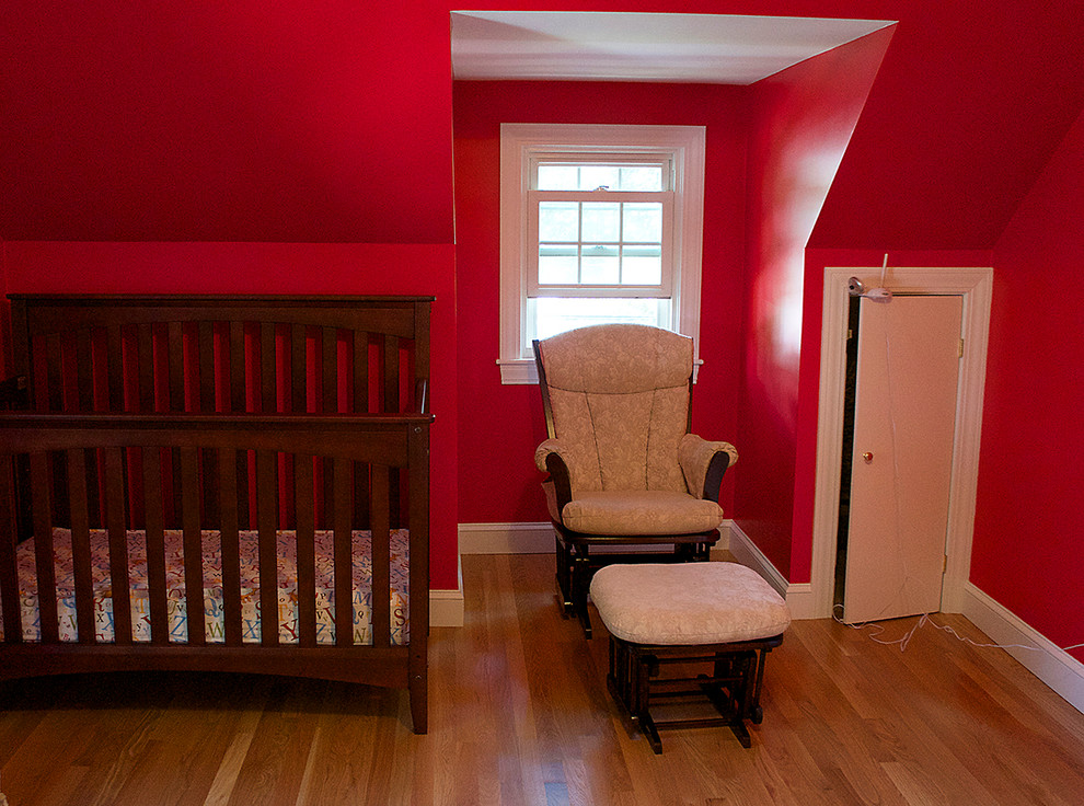 Inspiration pour une chambre de bébé neutre traditionnelle de taille moyenne avec un mur rouge et un sol en bois brun.