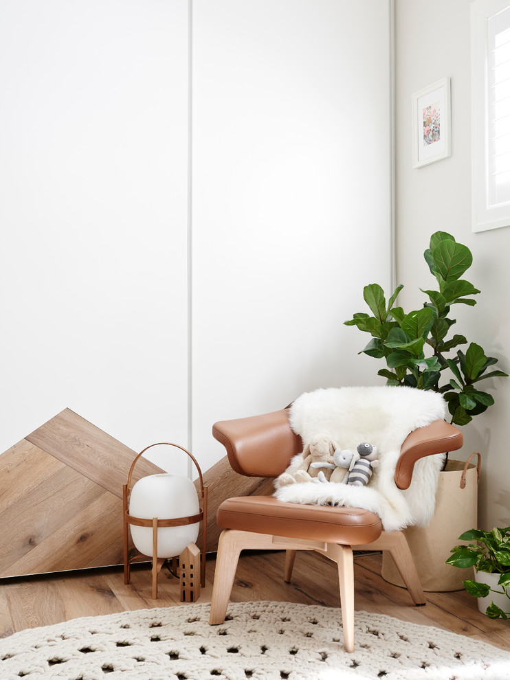 Diseño de habitación de bebé contemporánea con suelo de madera clara