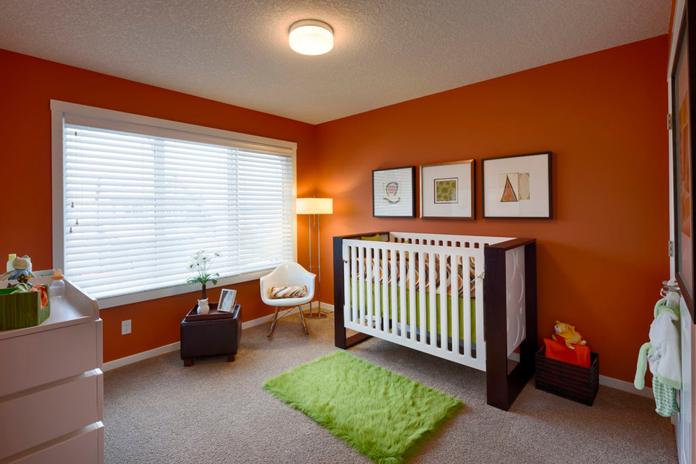 Esempio di una cameretta per neonati neutra contemporanea di medie dimensioni con pareti arancioni e moquette