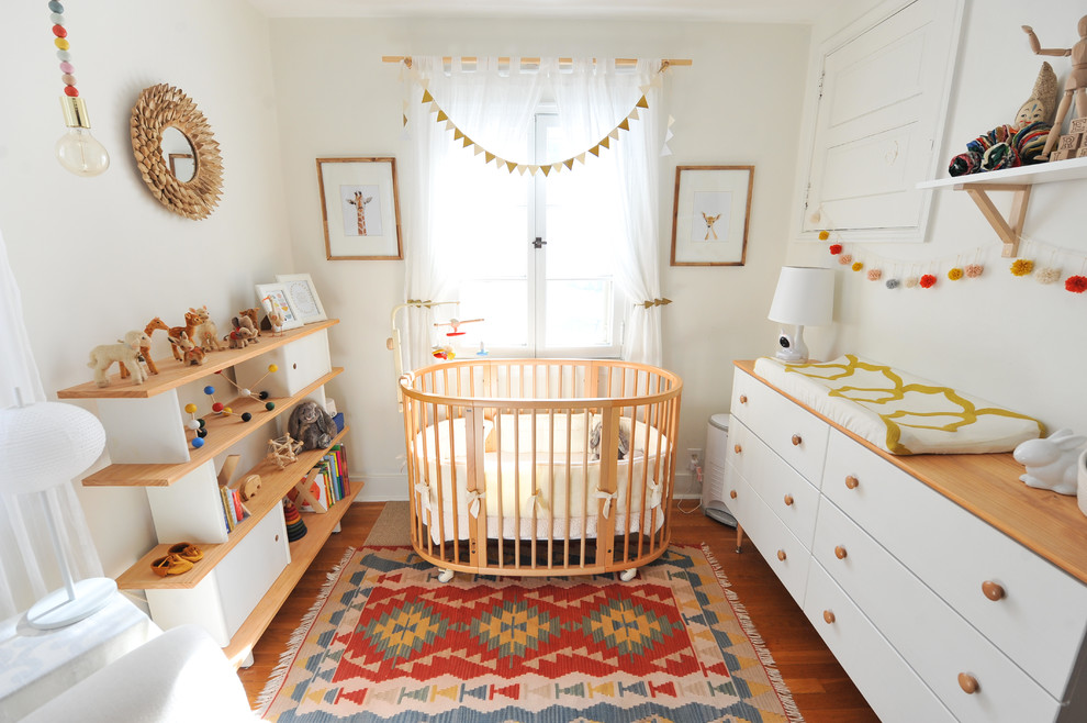Diseño de habitación de bebé neutra nórdica con paredes blancas, suelo naranja y suelo de madera en tonos medios