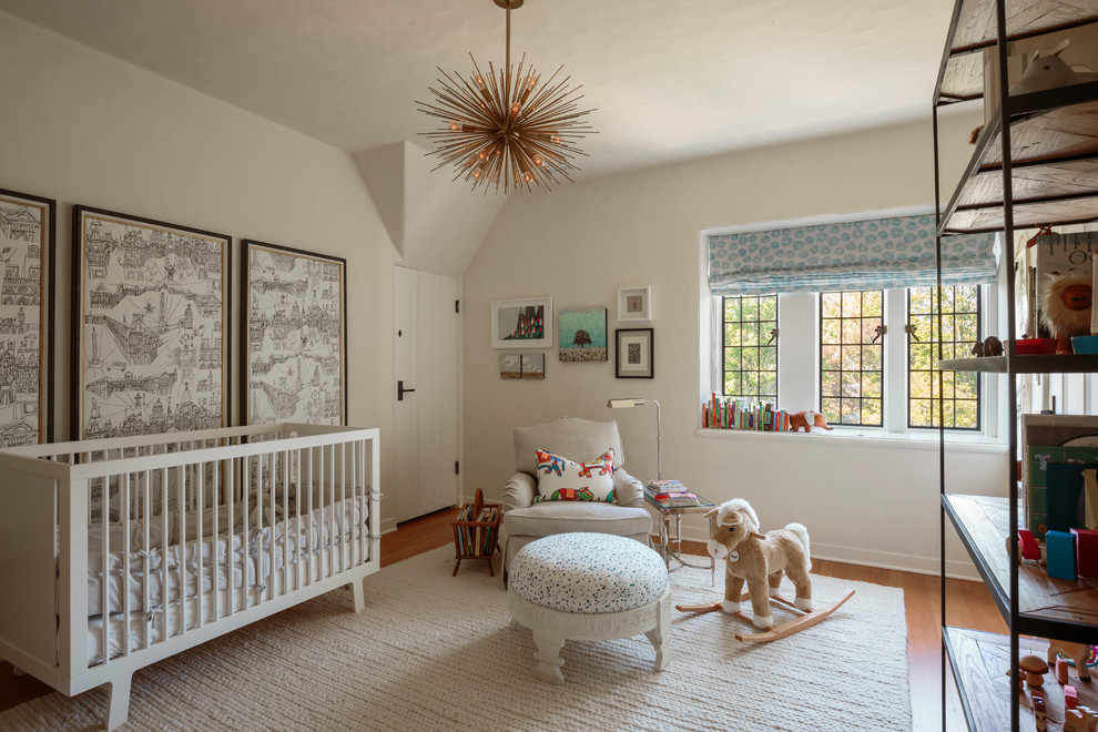 Cette photo montre une chambre de bébé chic avec un mur blanc, un sol en bois brun et un sol beige.