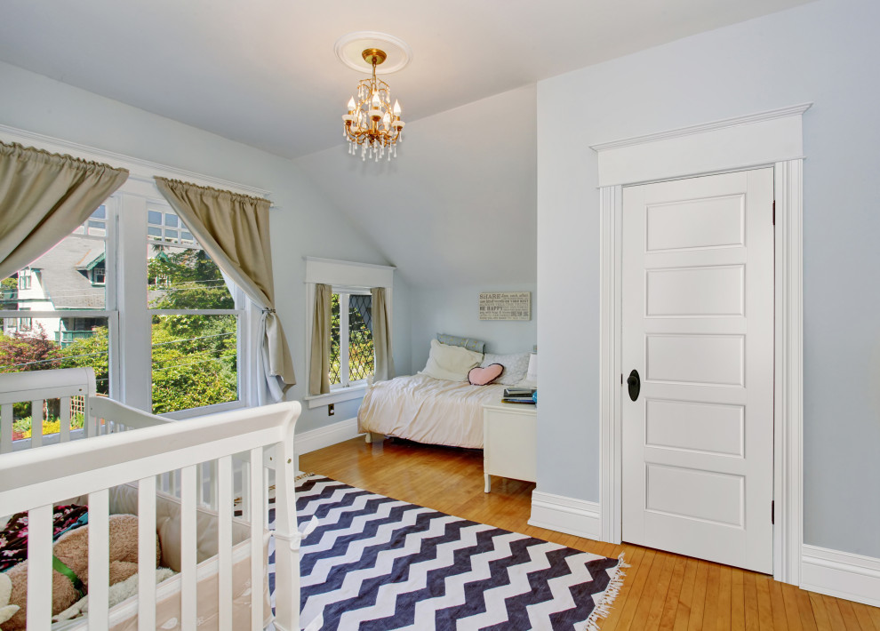 Exemple d'une grande chambre de bébé neutre chic avec un mur bleu, un sol en bois brun et un sol marron.