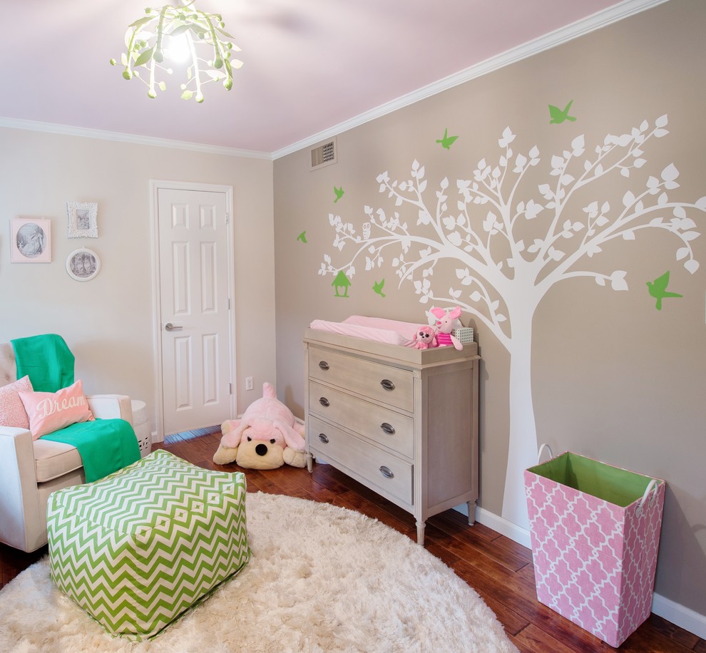 Cette photo montre une chambre de bébé fille chic de taille moyenne avec un mur gris et un sol en bois brun.