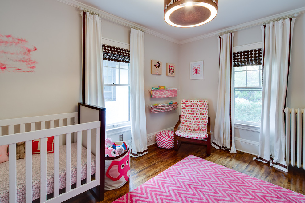 Réalisation d'une chambre de bébé fille tradition avec un mur beige et parquet foncé.