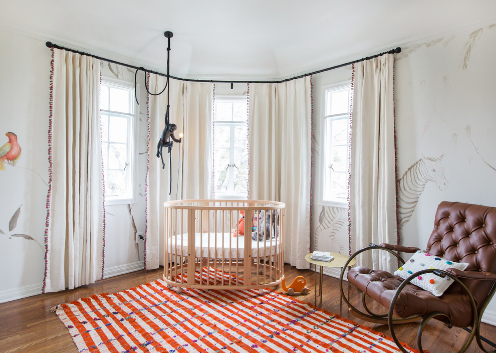 Cette photo montre une chambre de bébé neutre chic de taille moyenne avec parquet foncé, un sol marron et un mur blanc.