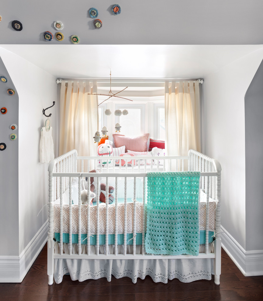 Imagen de habitación de bebé neutra tradicional renovada con paredes grises y suelo de madera oscura