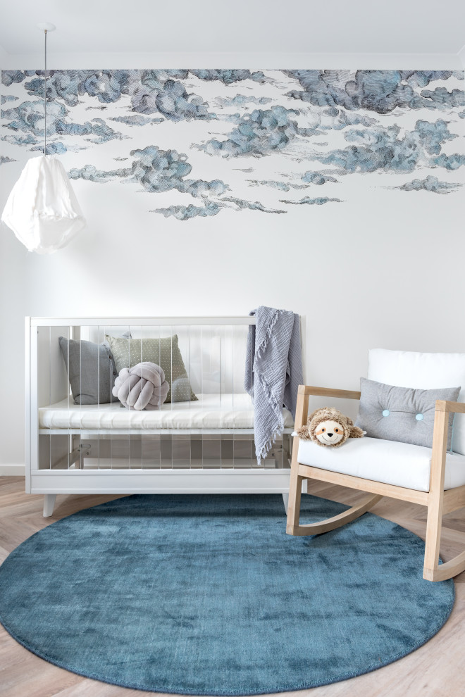 Imagen de habitación de bebé neutra contemporánea con paredes multicolor, suelo de madera clara, suelo beige y papel pintado