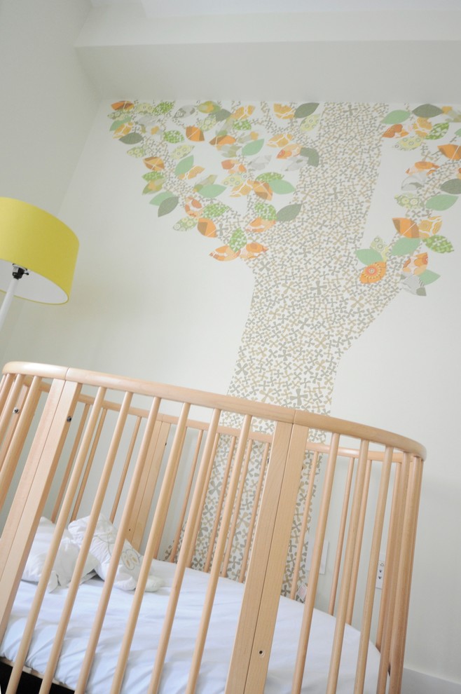 Cette image montre une chambre de bébé neutre minimaliste de taille moyenne avec un mur multicolore et parquet foncé.