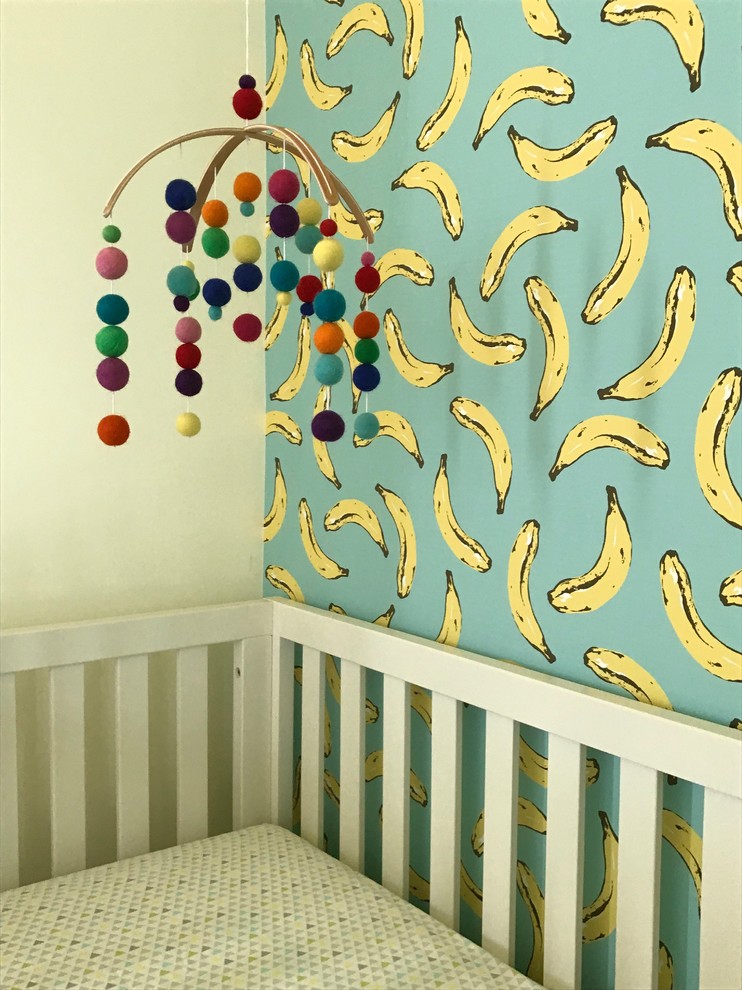 Modelo de habitación de bebé neutra grande con paredes amarillas, suelo de madera en tonos medios y suelo marrón