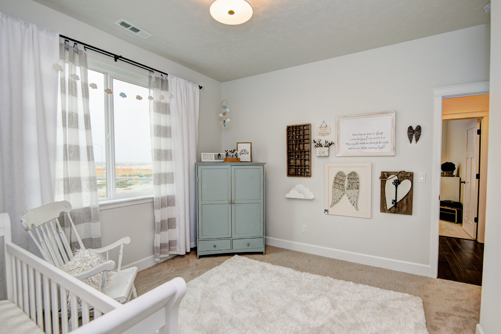 Modelo de habitación de bebé neutra rústica de tamaño medio con paredes blancas, moqueta y suelo beige