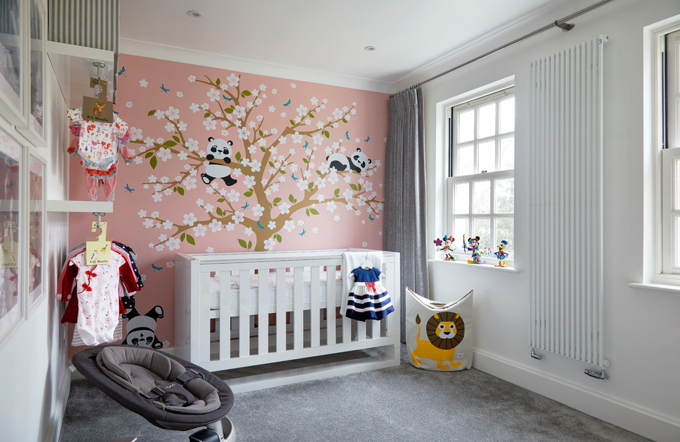 Modelo de habitación de bebé niña actual de tamaño medio con paredes rosas, moqueta y suelo gris