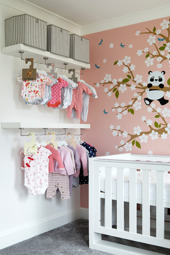 Modelo de habitación de bebé niña contemporánea de tamaño medio con paredes rosas, moqueta y suelo gris
