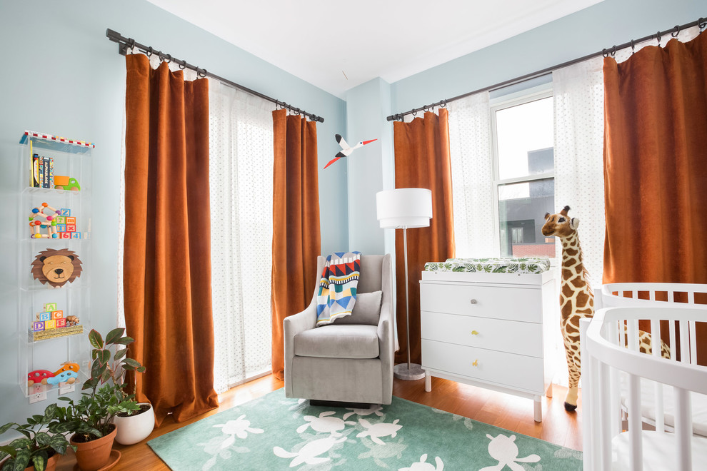 Immagine di una cameretta per neonati neutra design con pareti blu, pavimento marrone e pavimento in legno massello medio