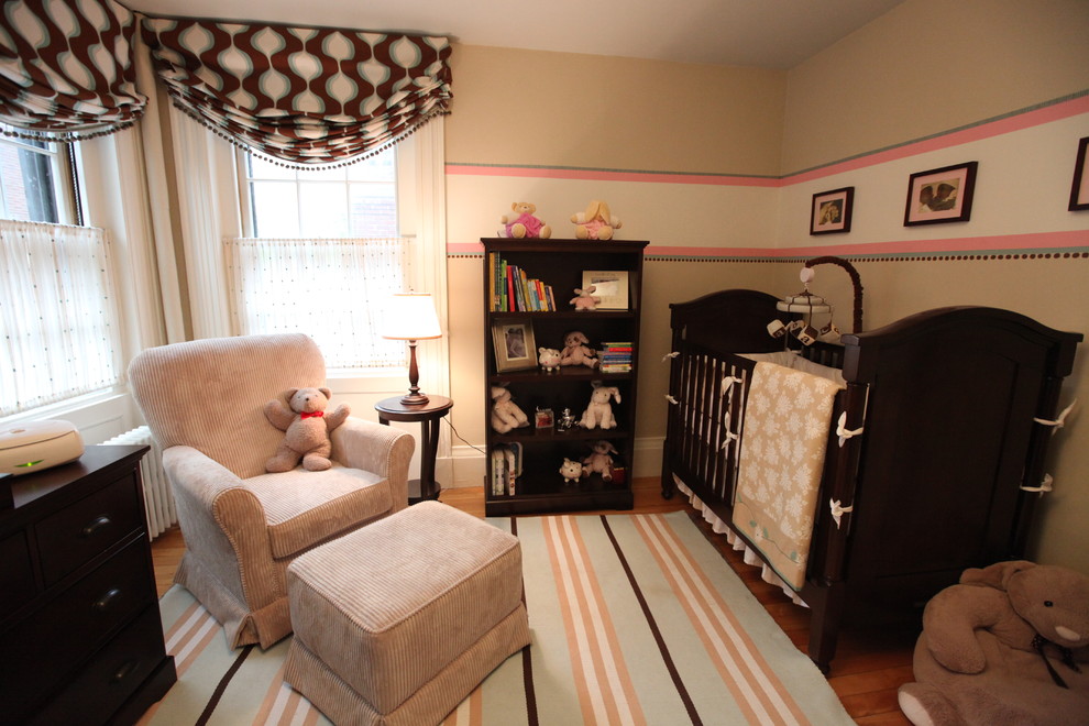 Idée de décoration pour une chambre de bébé neutre design avec un mur beige et un sol en bois brun.