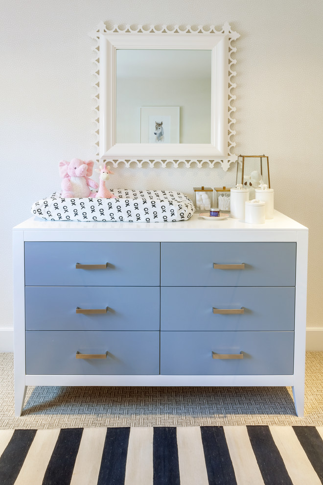 This is an example of a medium sized modern nursery for girls in New York with beige walls and carpet.