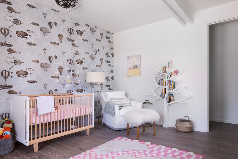 Cette image montre une chambre de bébé fille design avec un mur multicolore, un sol en bois brun et un sol marron.