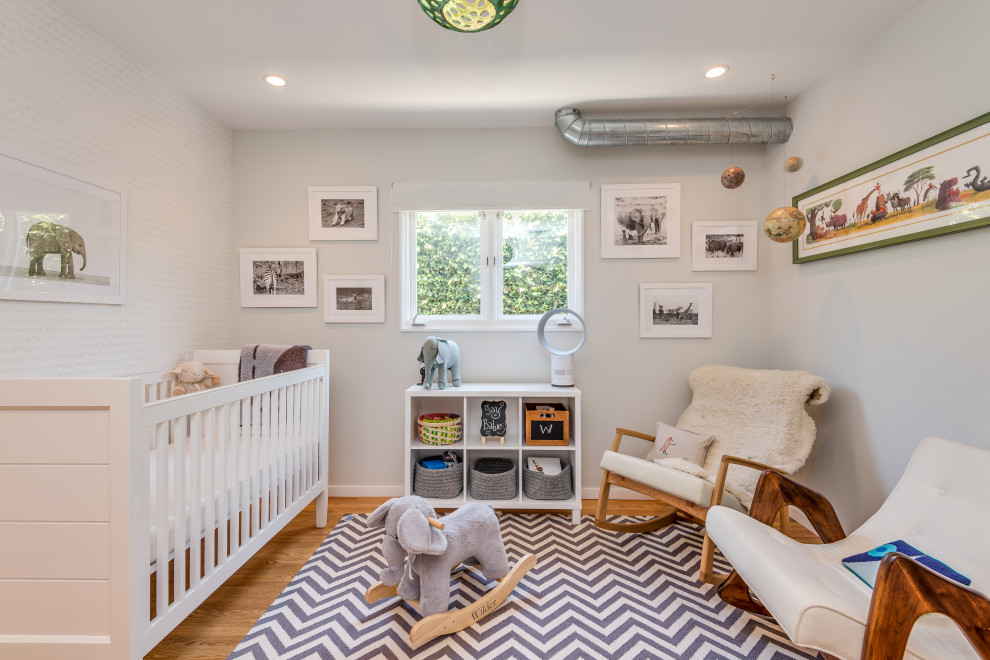 Imagen de habitación de bebé neutra vintage con paredes blancas y suelo de madera en tonos medios