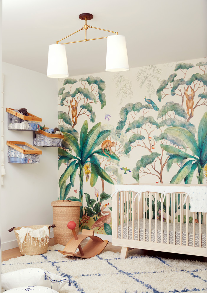 Cette photo montre une chambre de bébé neutre tendance avec un mur blanc, un sol en bois brun et un sol marron.