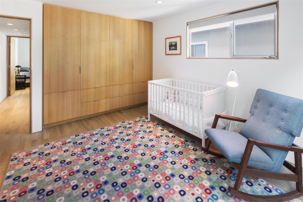Imagen de habitación de bebé neutra vintage con paredes grises y suelo de madera en tonos medios