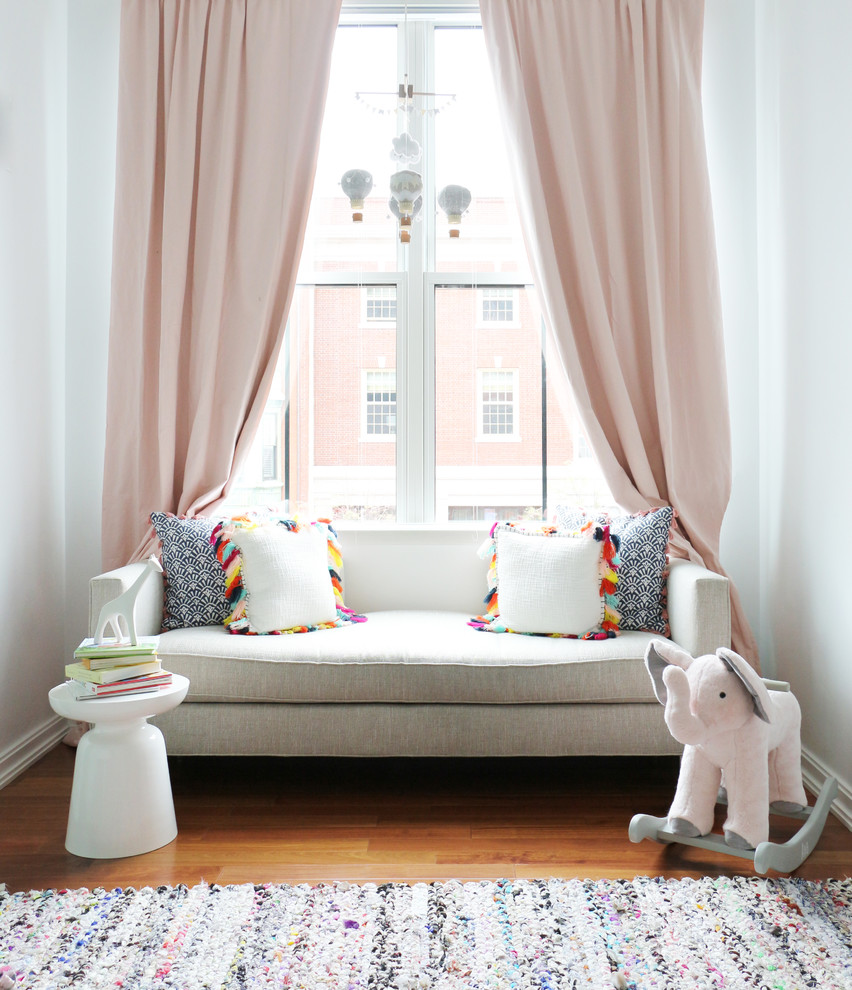 Réalisation d'une chambre de bébé fille minimaliste de taille moyenne avec un mur blanc, un sol en bois brun et un sol marron.
