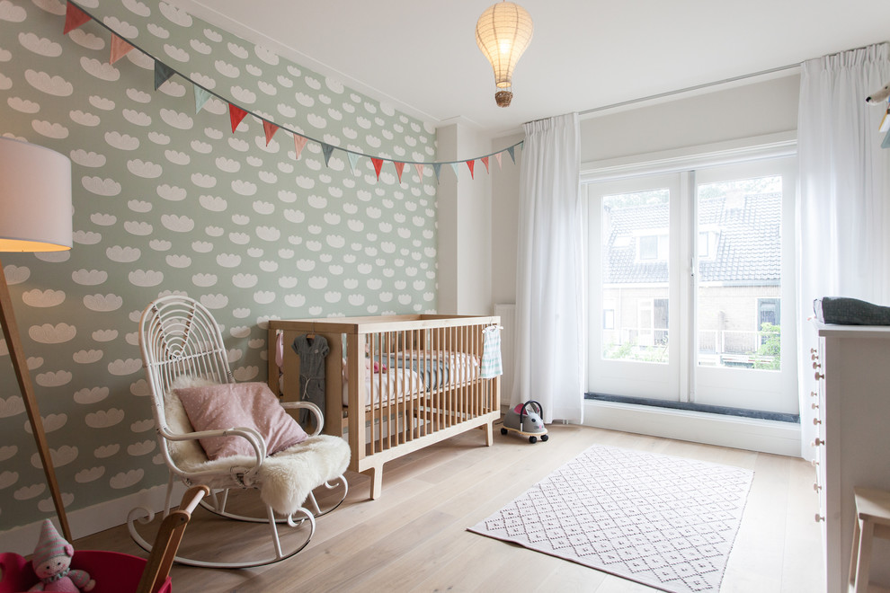 Inredning av ett skandinaviskt babyrum, med vita väggar, ljust trägolv och beiget golv