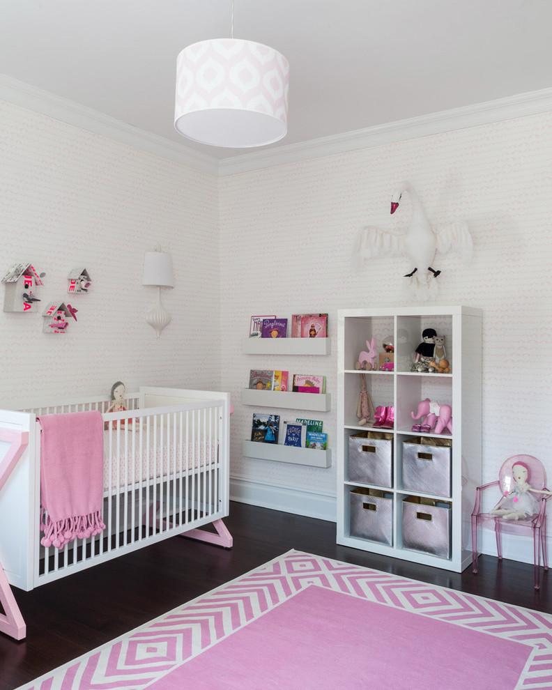 Réalisation d'une chambre de bébé fille design avec un mur blanc et parquet foncé.