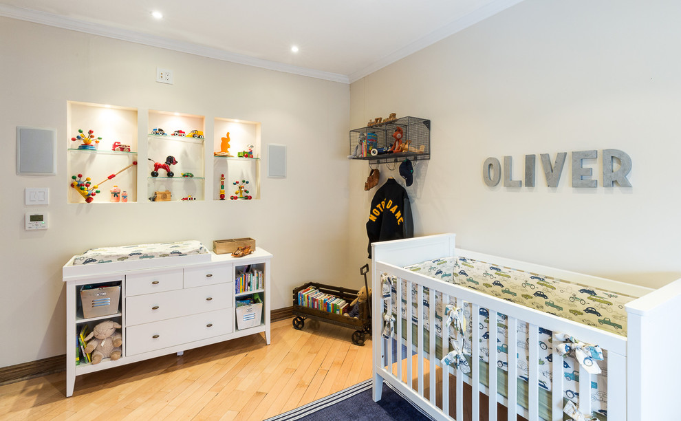 Modelo de habitación de bebé niño ecléctica de tamaño medio con paredes beige y suelo de madera clara