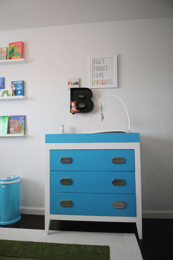 This is an example of a small modern nursery for boys in Orange County with white walls and medium hardwood flooring.