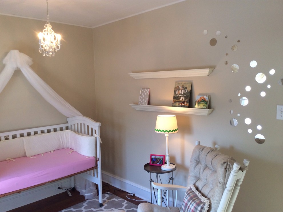 Réalisation d'une chambre de bébé neutre tradition de taille moyenne avec un mur beige et un sol en bois brun.