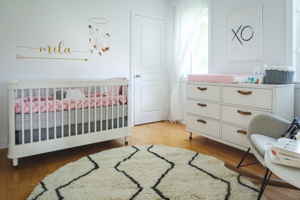 Diseño de habitación de bebé niña nórdica pequeña con paredes blancas y suelo de madera clara