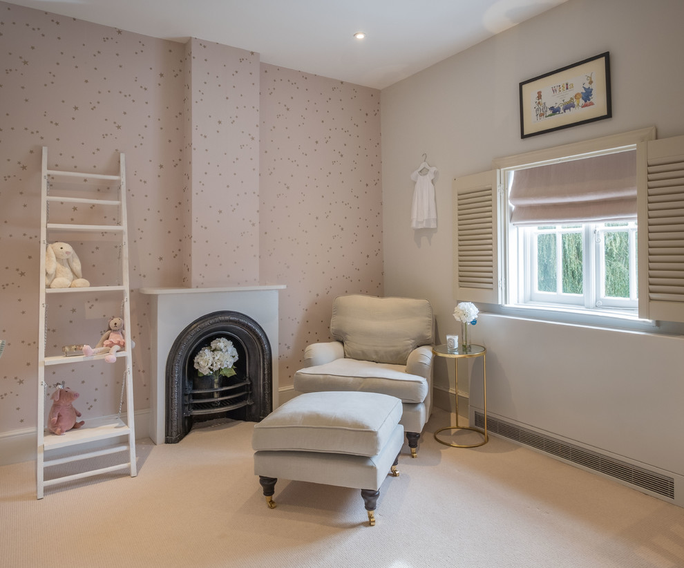 This is an example of a medium sized traditional nursery for girls in Hampshire with pink walls, carpet, white floors and a chimney breast.