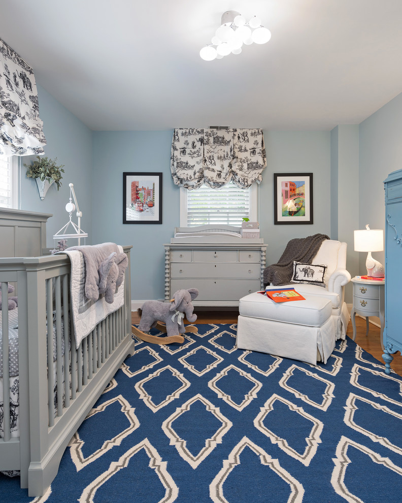 Aménagement d'une chambre de bébé garçon classique de taille moyenne avec un mur bleu et un sol en bois brun.