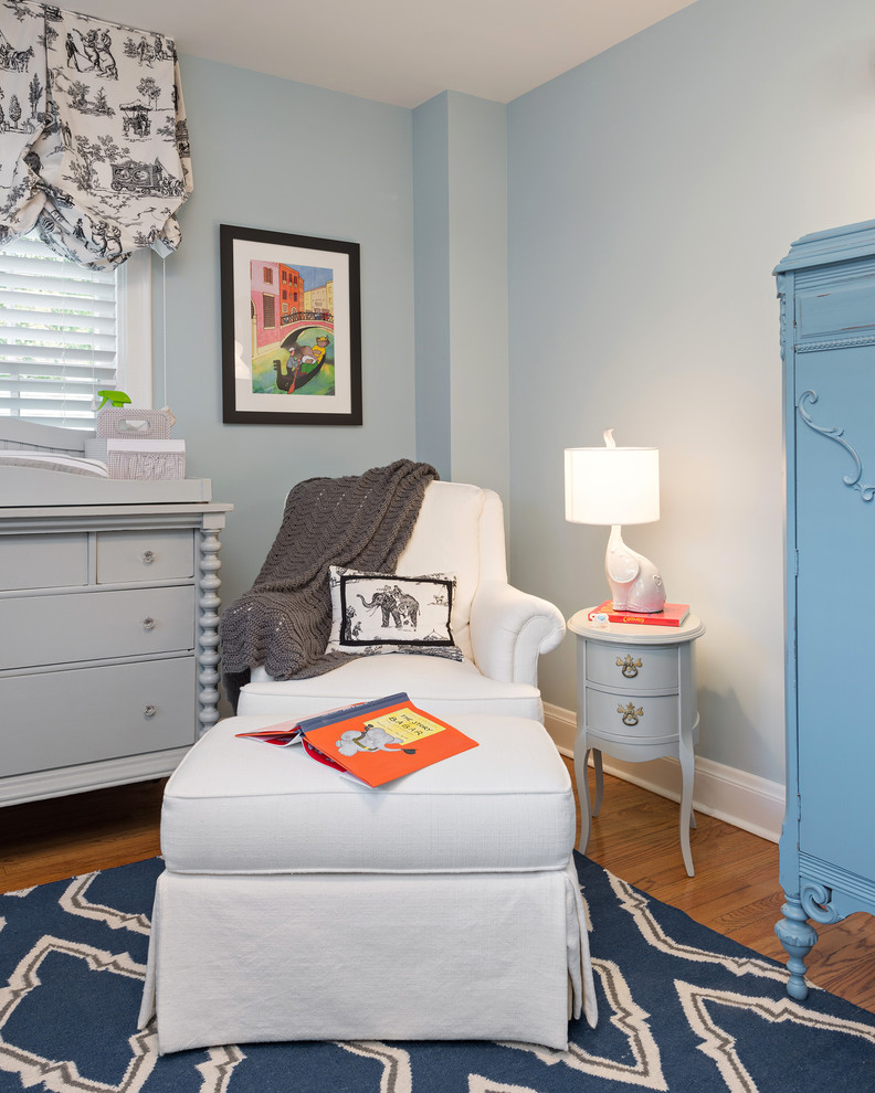 Diseño de habitación de bebé niño tradicional de tamaño medio con paredes azules y suelo de madera en tonos medios