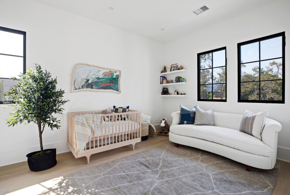 This is an example of a large classic gender neutral nursery in Los Angeles with white walls, light hardwood flooring, beige floors and a coffered ceiling.