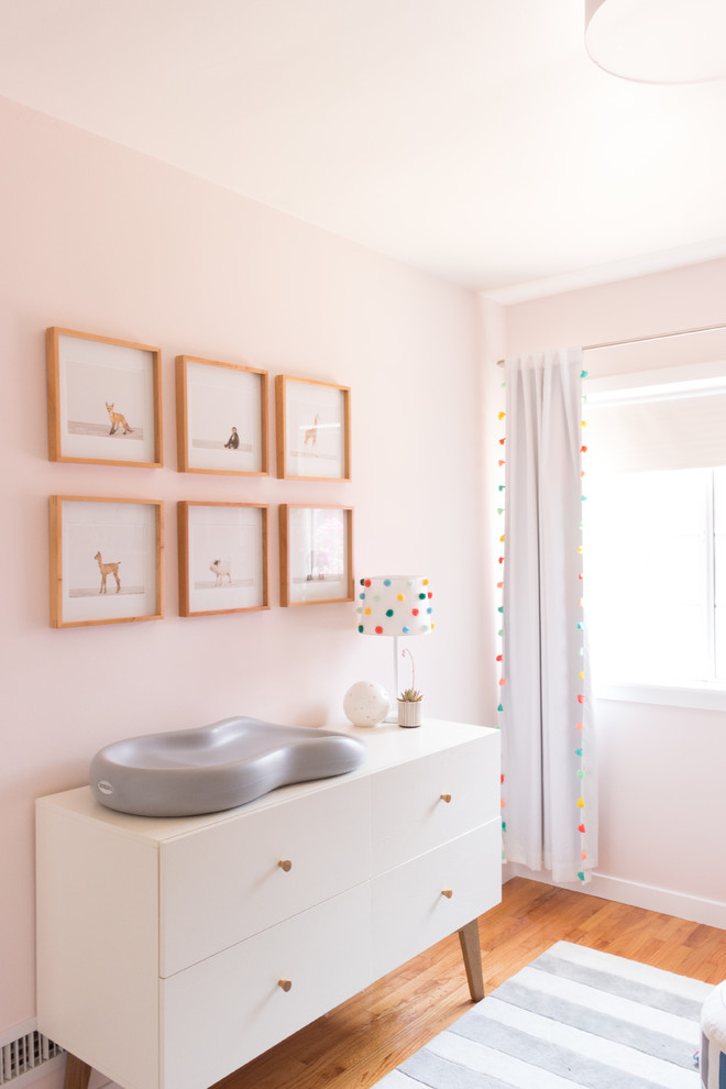 Modelo de habitación de bebé niña bohemia pequeña con paredes rosas, suelo de madera clara y suelo amarillo