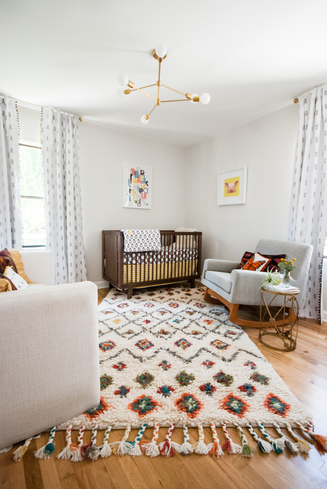 Aménagement d'une chambre de bébé neutre scandinave avec un mur blanc et parquet clair.