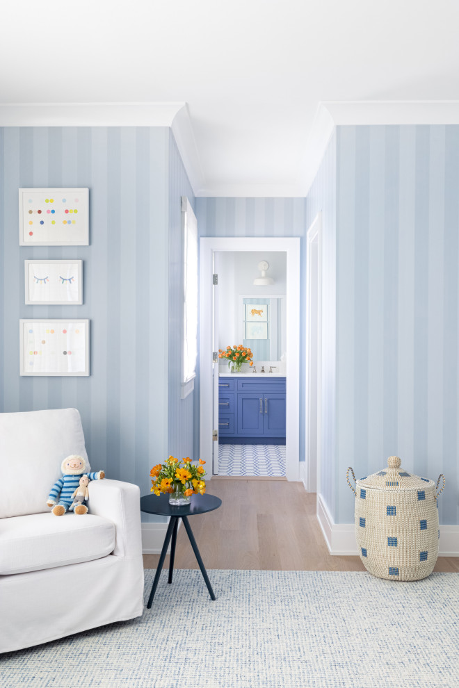Design ideas for a large classic nursery for boys in New York with blue walls, light hardwood flooring and brown floors.