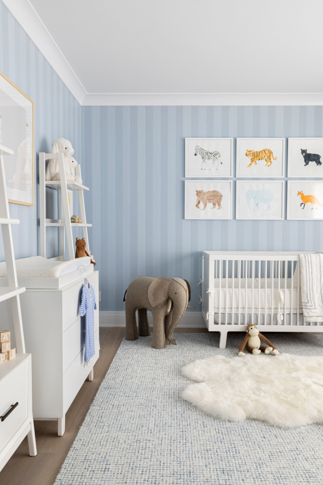 Photo of a large classic nursery for boys in New York with blue walls, light hardwood flooring and brown floors.