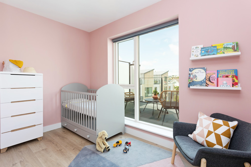 Diseño de habitación de bebé niña escandinava pequeña con paredes rosas y suelo laminado