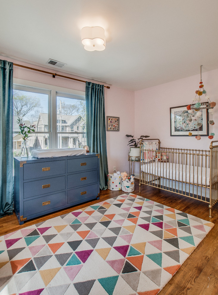 Aménagement d'une chambre de bébé neutre classique de taille moyenne avec un mur rose, parquet foncé et un sol marron.