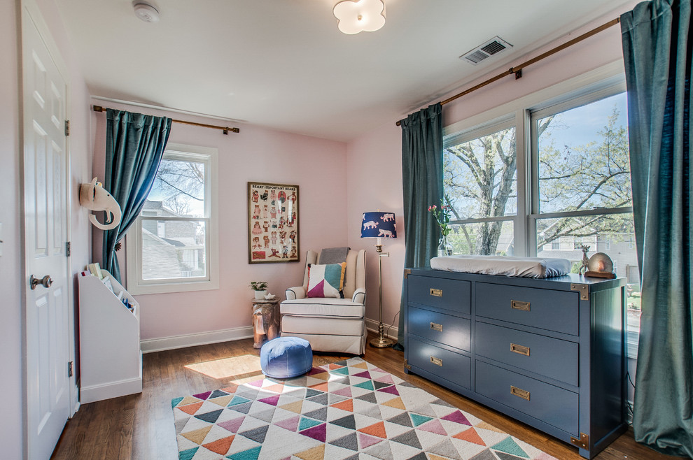 Imagen de habitación de bebé neutra clásica de tamaño medio con paredes rosas, suelo de madera oscura y suelo marrón