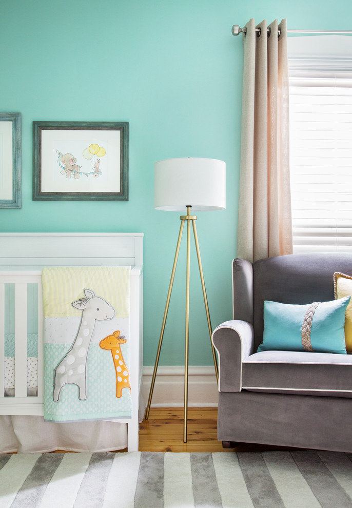 Ejemplo de habitación de bebé neutra clásica renovada con paredes azules y suelo de madera clara