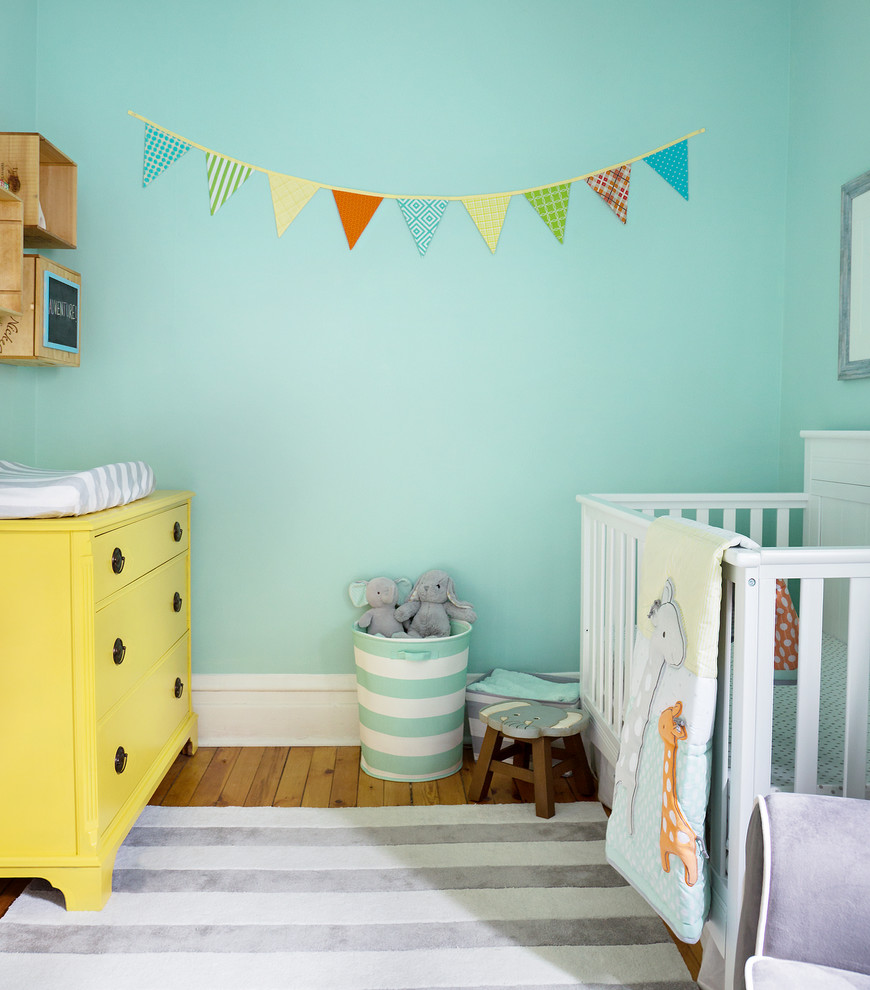 Imagen de habitación de bebé neutra clásica renovada con paredes azules y suelo de madera clara