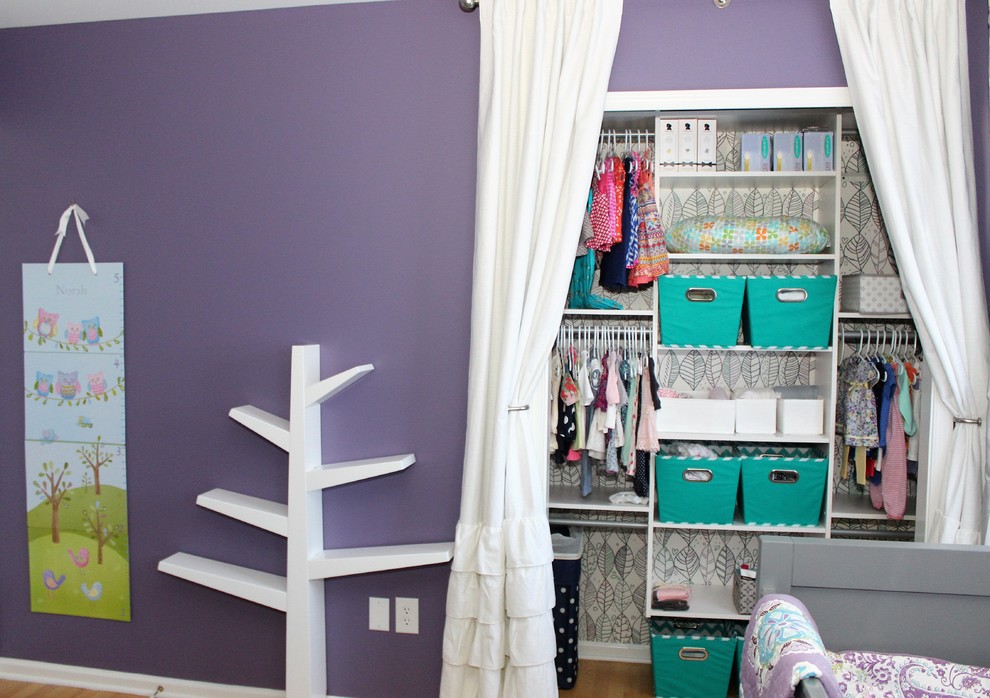 Immagine di una piccola cameretta per neonata classica con pareti viola e parquet chiaro